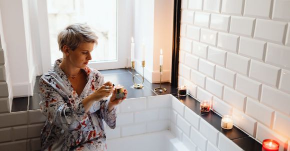 Bathroom Lighting - Man Lighting a Scented Candle Wearing a Printed Bathrobe Sitting on Bathtub