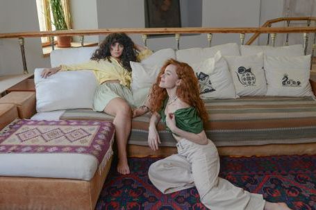 Rug Patterns - Ginger Woman Sitting on the Carpet Beside Woman on Couch
